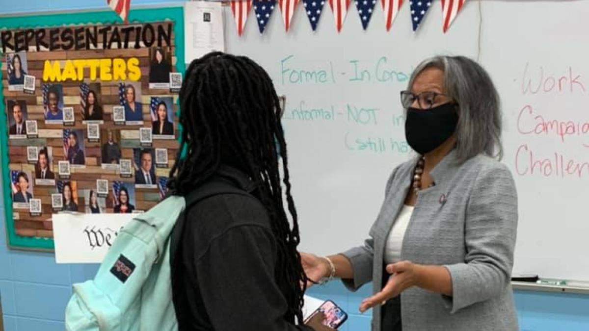 Rep. Kelly talks with a student in a classroom.
