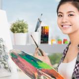 Student artist smiling with paint brush and paint palette